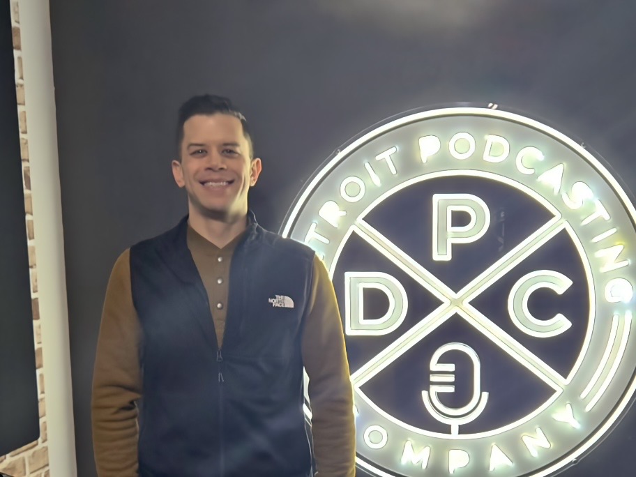 David Juan in front of a sign that reads DPC: Detroit Podcasting Company